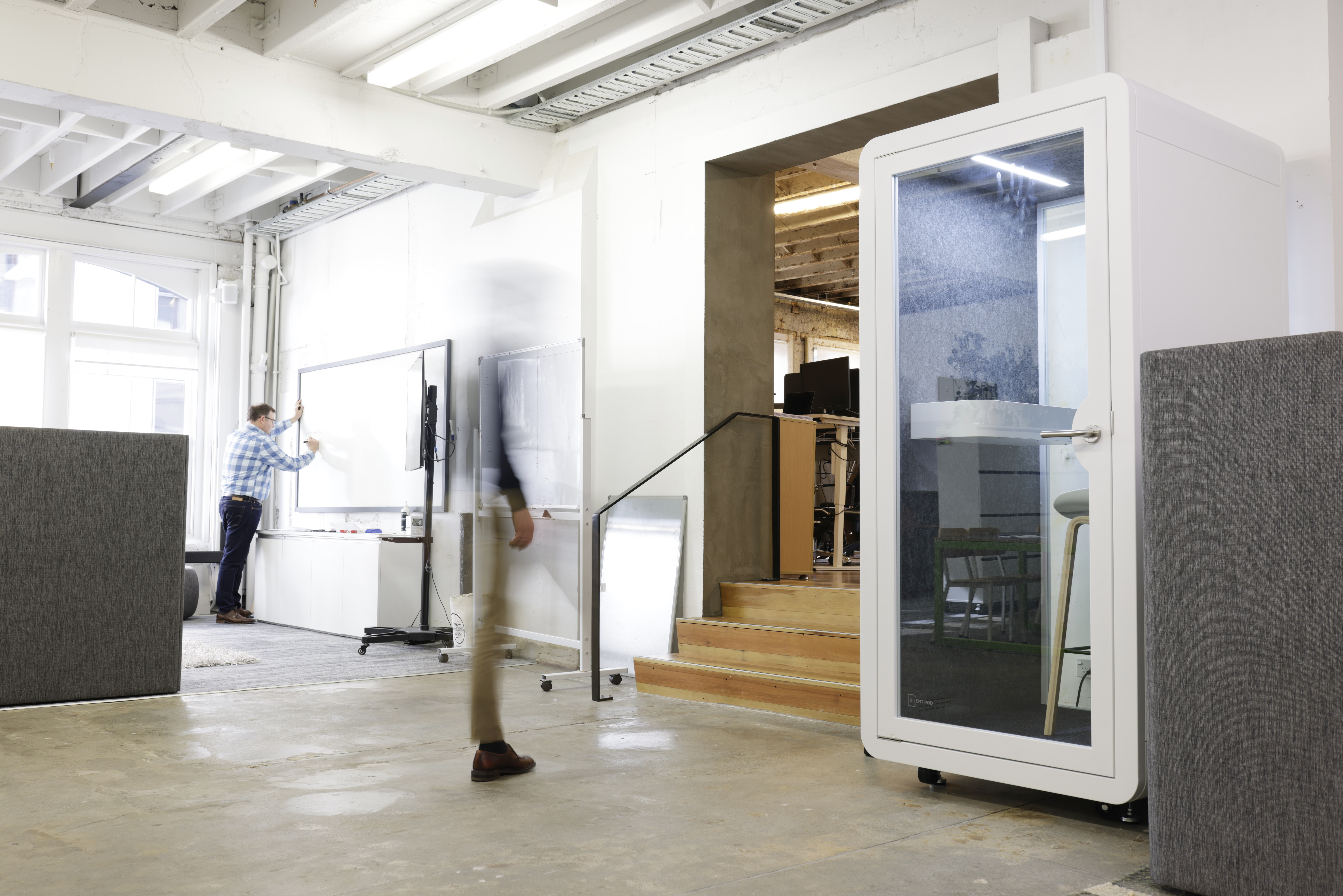 Single Pod in a modern open-plan office, positioned near a meeting area for quick access to quiet space.