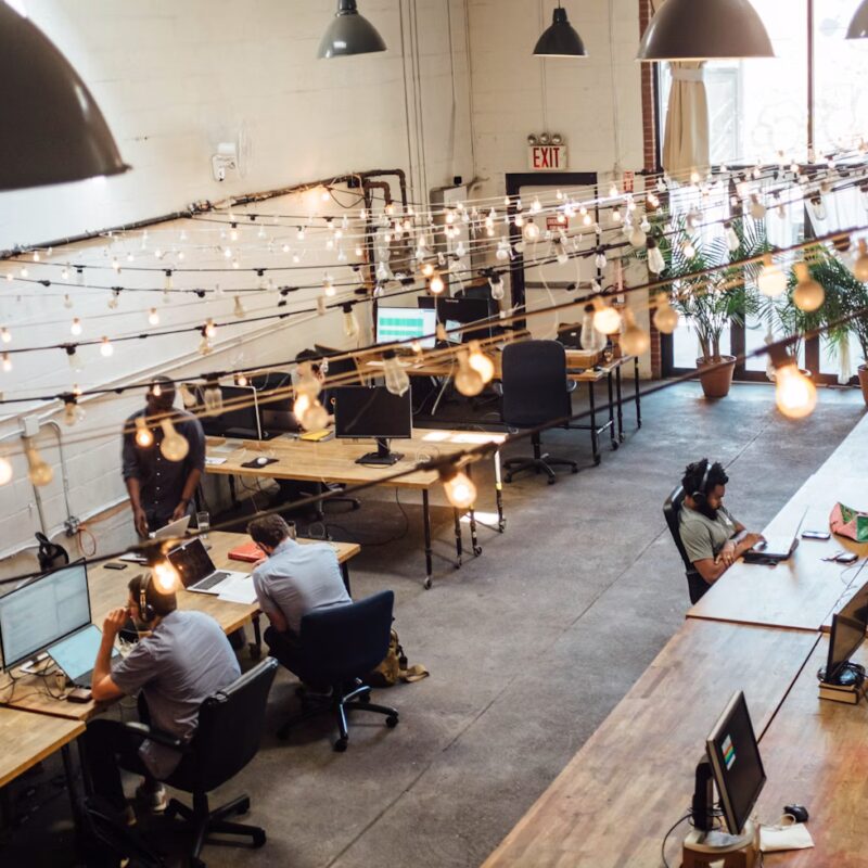 An image of a cool coworking space with fairy lights and people on computers.