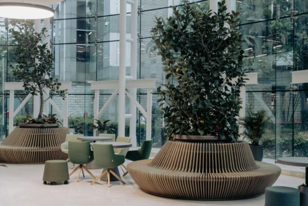 The image shows a modern office lobby or waiting area with a contemporary design. The space features large floor-to-ceiling windows that allow natural light to flood the area, creating a bright and airy atmosphere.